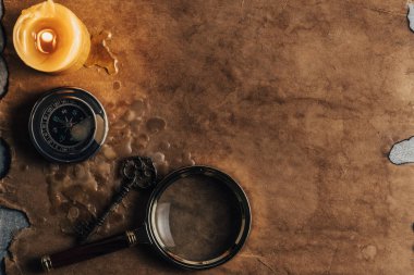 Büyüteç, klasik anahtar, pusula ve mum arka planda eski ve kirli kağıt