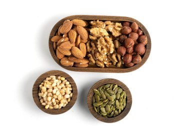 Beyaz arka planda izole edilmiş ahşap kaselerde karışık fındıklar. Üst görünüm