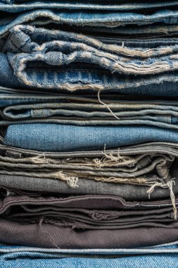 Bir yığın mavi ve gri kot pantolon. Pantolon desenli bir arka plan. Denim arkaplanı