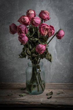 Ahşap bir masada cam bir kavanozda kurumuş güller.