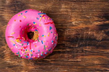 Ahşap arka planda renkli serpiştirilmiş pembe çörek. Üst görünüm