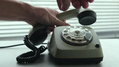Elle eski moda bir telefonun ahizesini alır ve çevirmeli arama ile numarayı çevirir. Perdelerle pencerenin arkasında. Yakın çekim..