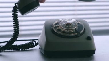 El, arka plan perdelerine eski bir disk telefonu koyar. Yakın çekim..