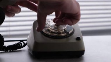 İnsan eski, eski bir telefonu çevirerek telefon numarasını eliyle çevirir. Yakın çekim..