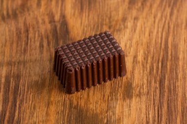 Tahta arka planda çikolatalı şeker, yakın plan.