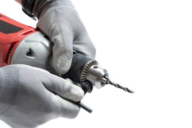 Beyaz arka planda gri eldivenli bir elektrikli matkap.