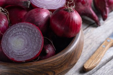 Tahta masadaki kasede taze dilimlenmiş kırmızı soğan, yakın plan. Sağlıklı beslenme