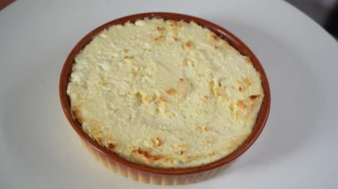 Sade vejetaryen peynirli kek yakın plan döner döner döner. Kahverengi tabakta beyaz arka planda dönen yuvarlak peynirli kek. Üst Manzara. Ev yapımı yemek, peynirli kremalı tart. Yüksek kalite 4k görüntü