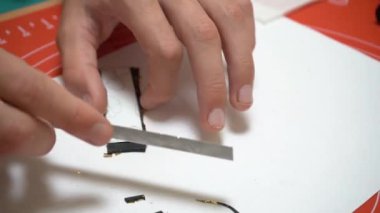 El yapımı aksesuarlar atölyesi. Polimer kil, özel bir bıçakla siyah kil parçaları kesiyor. Esnaf, usta plastikle çalışır. Seçici odaklanma. Yüksek kaliteli FullHD görüntüler