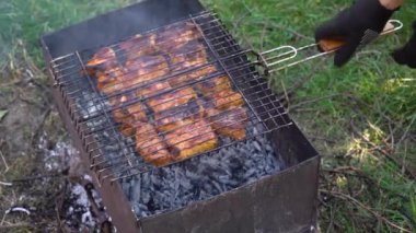 Arka bahçede barbekü, arka planda ızgara yemek. Dışarıdaki ızgarada et parçaları. Açık havada yemek pişirmek, kızarmış kebaplı demir ızgara. 4K video. 4K video.