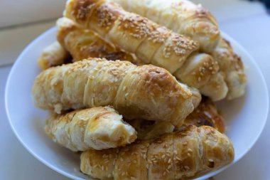 Kahvaltıda atıştırmalık olarak beyaz tabakta susamlı ev yapımı börek. Ev yemeği yakın çekim. Yüksek kalite fotoğraf