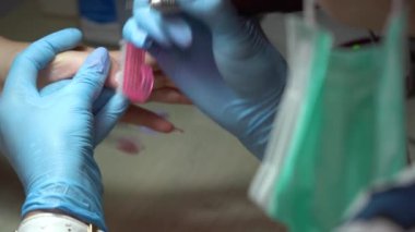 Uzun tırnaklı manikür. Usta ojeyi profesyonel elektrikli aletle söker. Mavi eldivenli bir manikürcü yakın plan güzellik salonunda işlem yapıyor. Yüksek kalite 4k görüntü