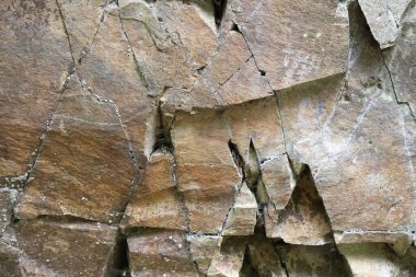 Doğa kökenli. Kalıplı kayalık bir yüzey, güneş ışığı altında sayısız karmaşık çatlaklar ve çatlaklar gösterir. Renkler ten renginden griye, jeolojik özellikler