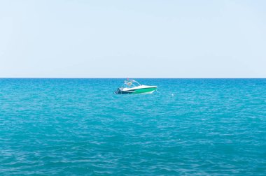 Mavi deniz suyunda, açık gökyüzünün altında hızlı bir yat. Güneşli bir gün ufkunda okyanusta tek başına bir tekne. Yüksek kalite fotoğraf