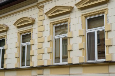 Eski binanın bir parçası. Açık sarı renkli beyaz çerçeveli pencereler. Mimari stil klasisizmi. Gayrimenkul yakınlığı, eski evin penceresi. Yüksek kalite fotoğraf