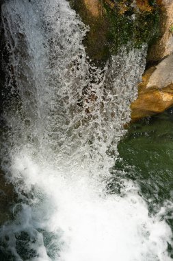 Kayaların üzerinde çağlayan şelaleler, sudaki su sıçramaları ve dalgalanmalar, yemyeşil sularla çevrili, barış ve doğal güzelliği çağrıştırıyor. Yüksek kaliteli dikey hareket fotoğrafı