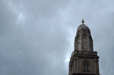 Şehirdeki tarihi bir binanın akşam manzarası. Gökyüzü bulutlu bir günde bir kilise kulesinin arka planında