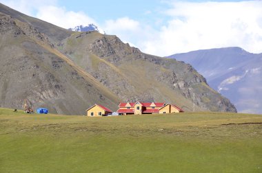 Dağ yamacına modern bir tasarım yapılmış ahşap evler. Dağın eteğindeki çekici ahşap evler ve arka planda çıplak dağlar. Arkaplan veya dergi için yüksek kaliteli doğa görüntüsü