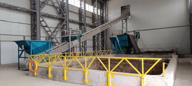 Bir atık işleme tesisinde ham madde depolama kapasitesi, yeşil metal sığınaklar ve bir şerit taşıyıcı. Kapalı metal yapılandırılmış boşluk.