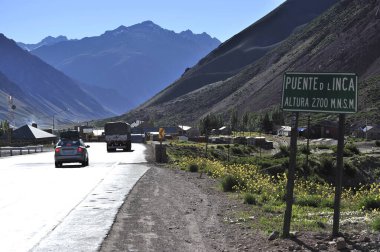 l inca bridge Height 2700 m.a.s.l. A road through a small settlement built at the foot of a mountain. A road sign on the side of the road.