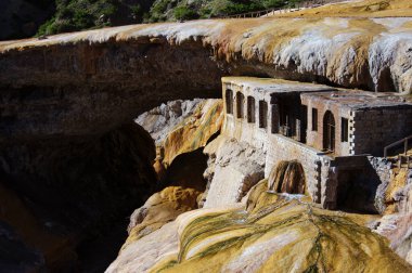 Kayanın altında egzotik görünümlü taş bir bina. Yosun kaplı eski bir kale. Eski bir taş binanın altından kanalizasyon akıyor..