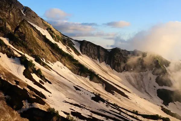 Gün batımında karlı dağların fotoğrafı. Sisin içindeki dağlar.