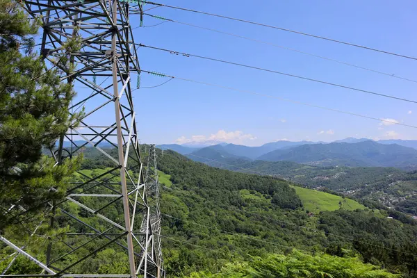 Mavi gökyüzü ve dağların arkasında elektrik iletim hatları var. Elektrik..