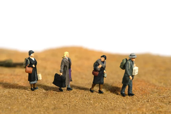 Miniature people toy figure photography. A group of refugee walking in the middle of desert, moving to refugee camp because of war conflict. Image photo
