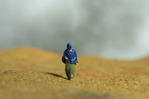 Miniature people toy figure photography. Loneliness and solitude. Women wearing veil walking in the middle of dessert alone. Image photo
