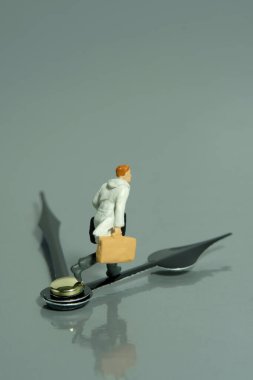 Minyatür minyatür insanlar oyuncak figürlü fotoğrafçılık. Siyah saat yönünde koşan bir işadamı evrak çantası taşıyor. Gri arka planda izole edilmiş. Resim fotoğrafı.
