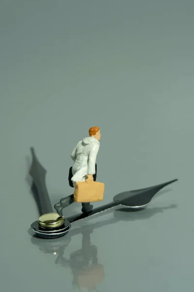 Miniature tiny people toy figure photography. A businessman running above black clockwise carrying briefcase. Isolated on grey background. Image photo