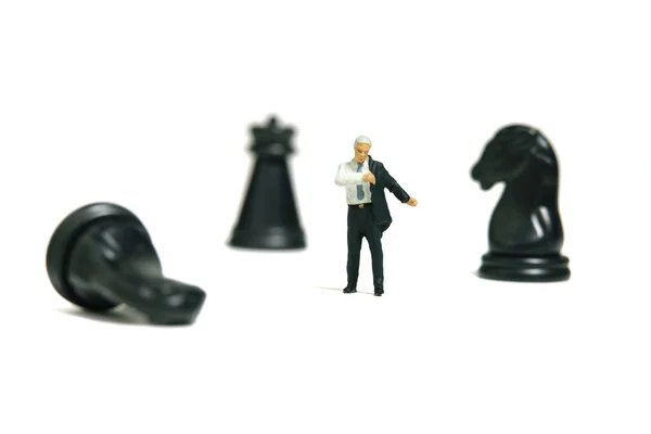 Miniature tiny people toy figure photography. Business preparation concept. A businessman getting ready wearing suit standing in front of chess pawn. Isolated on a white background. Image photo