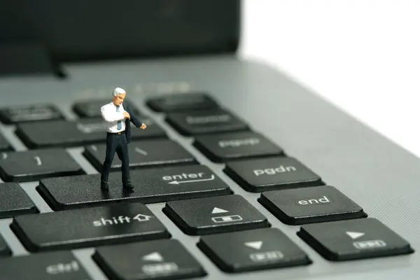 stock image Miniature tiny people toy figure photography. A businessman getting ready wearing suit standing above notebook keyboard. Isolated on white background. Image photo