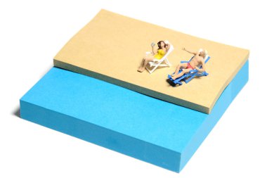 Yaratıcı minyatür insanlar oyuncak fotoğrafçılığı. Yapışkan notlar kurulumu. Sahildeki bankta takılan bir çift. Beyaz arka planda izole edilmiş. Resim fotoğrafı.