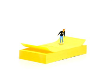 Creative miniature people toy figure photography. Sticky notes installation. A boy roller skater playing at skate park. Isolated on white background. Image photo