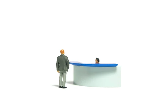 Miniature tiny people toy figure photography. A man with suit standing in front of receptionist desk. Isolated on a white background. Image photo