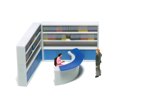 Miniature tiny people toy figure photography. A businessman guest standing in front of receptionist desk at office. Isolated on a white background. Image photo