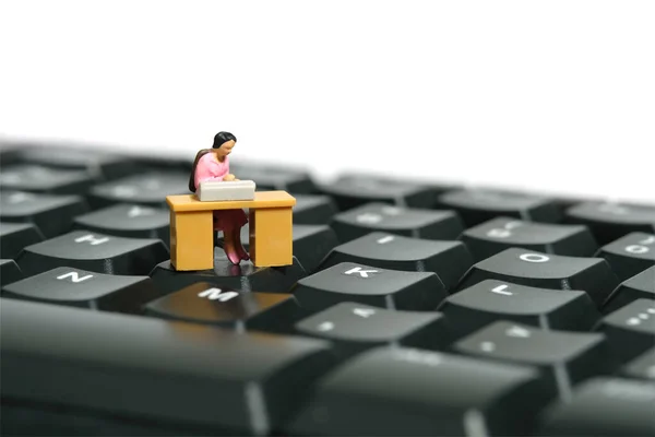 Miniature tiny people toy figure photography. A woman seat in the desk, working above keyboard. Isolated on a white background. Image photo