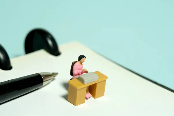Miniature tiny people toy figure photography. minutes of meeting. A woman office worker seat on desk above notebook. Image photo