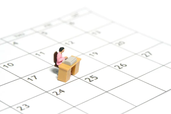 Miniature tiny people toy figure photography. Work schedule management concept. A businesswomen seat on his desk, above calendar. Isolated on a white background. Image photo