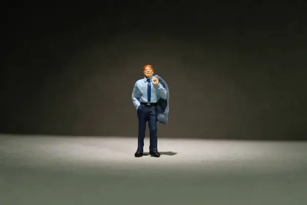 Miniature tiny people toy figure photography. A businessman standing alone with spotlight on dark room., shelf doubt dan introspection concept. Image photo