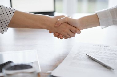 İş adamları kontrat kağıtlarının üzerinde el sıkışıyor. Tahta masaya yeni imzalanmış. Kapatın. Toplantıdaki avukatlar. Takım çalışması, ortaklık, başarı kavramı.