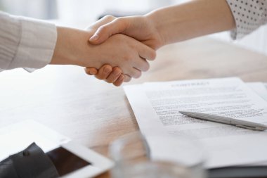 İş adamları kontrat kağıtlarının üzerinde el sıkışıyor. Tahta masaya yeni imzalanmış. Kapatın. Toplantıdaki avukatlar. Takım çalışması, ortaklık, başarı kavramı.