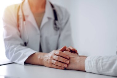 Doktor ve hasta klinikteki masada oturuyorlar. Dikkatimizi kadın doktorlara, güven veren kadınlara verelim. Kapatalım. Mükemmel tıbbi servis, empati ve tıp konsepti..