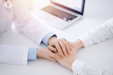 Doktor ve hasta klinikteki masada yan yana oturuyorlar. Kadın doktorlara odaklan. Kadına güven veren eller, sadece eller, yakın çekim. Tıp konsepti.