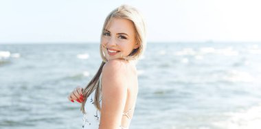 Mutlu sarışın kadın okyanus sahilinde mutlu mesut durup poz veriyor..