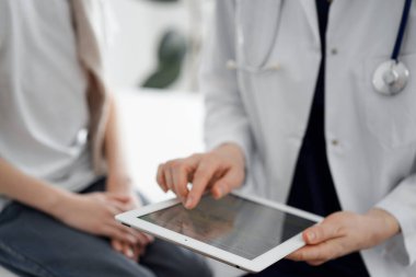 Doktor ve çocuk hasta. Doktor tablet bilgisayar kullanıyor ve çocuğu incelemeye hazır. Tıptaki ideal sağlık kavramı.