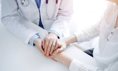 Doktor ve hasta klinikteki masada yan yana oturuyorlar. Kadın doktorlara odaklan. Kadına güven veren eller, sadece eller, yakın çekim. Tıp konsepti.