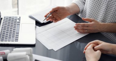 Müşteri için vergi sayarken hesap makinesi ve dizüstü bilgisayar kullanan kadın muhasebeci. İş denetimi ve finans kavramları.