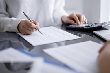 Müşteri için vergi sayarken hesap makinesi ve dizüstü bilgisayar kullanan kadın muhasebeci. İş denetimi kavramları.